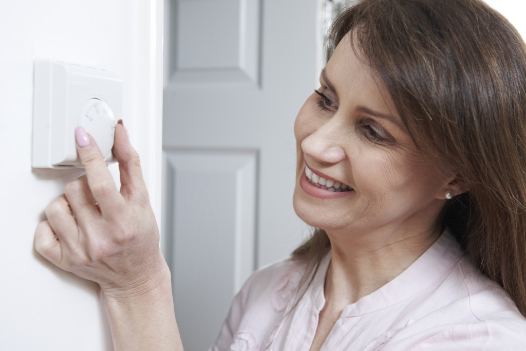 1024px x 683px - Woman Adjusting Thermostat On Central Heating Control - Fletcher Insulation