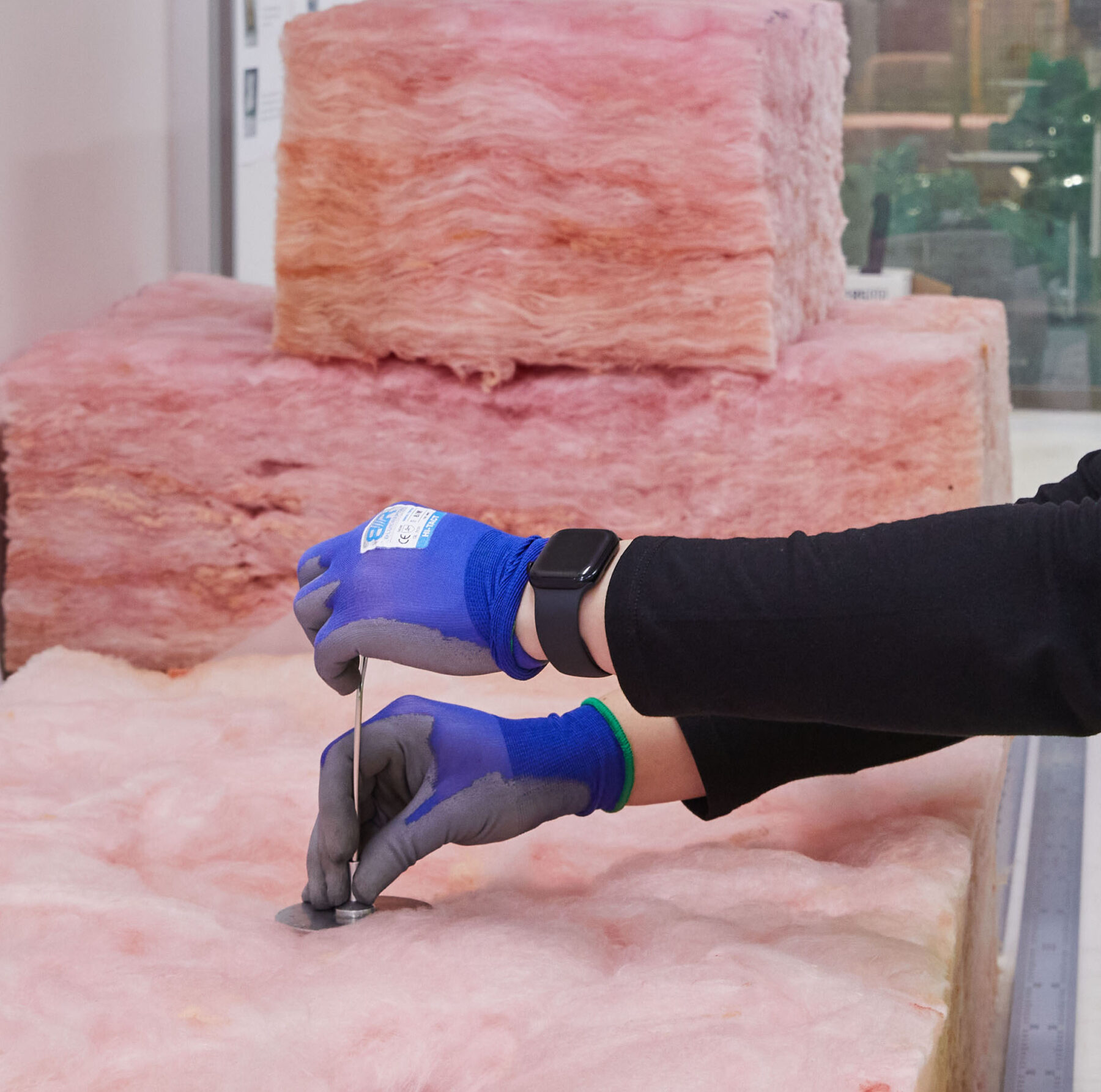 Fletcher Insulation person measuring Pink batt for quality assurance